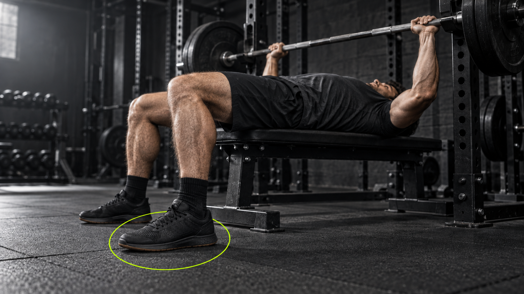 Lifter bench pressing with planted feet, highlighted by a subtle neon green accent.